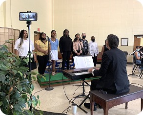 A choir singing beside a pianist at a keyboard