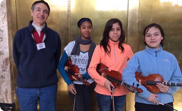 Rob Silvan with three young violinists holding their instruments